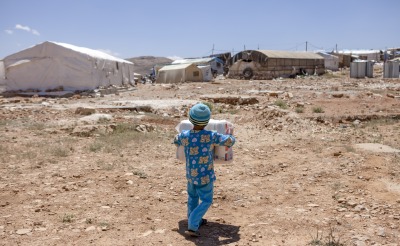 Ala, 7, carries back diapers for his little brother provided by Action Against Hunger in s settlement in Aarsal, Lebanon, near the Syrian border.